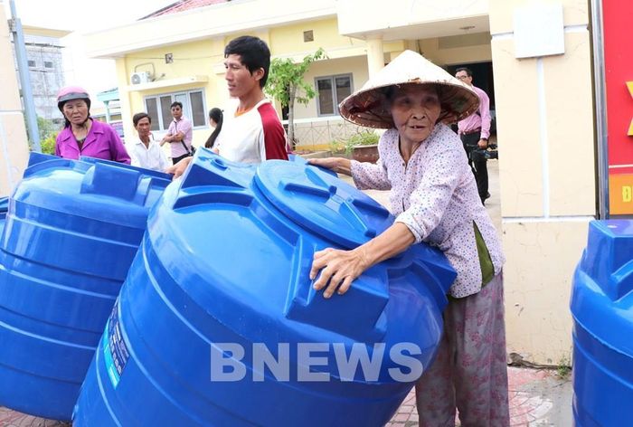 Người dân xã Long Hòa nhận bồn nước. Ảnh: Thanh Hòa-TTXVN