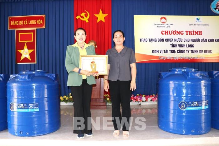 Phó Chủ tịch Ủy ban MTTQ Việt Nam tỉnh Vĩnh Long Nguyễn Thị Tuấn Thanh (bên phải) trao bằng khen của Chủ tịch UBND tỉnh cho đơn vị tài trợ chương trình. Ảnh: Thanh Hòa-TTXVN