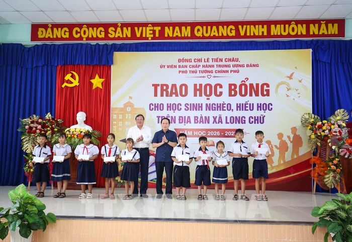 Các học sinh nghèo, hiếu học tại xã Long Chữ, tỉnh Tây Ninh nhận học bổng từ Phó Thủ tướng Chính phủ Lê Tiến Châu (phải) và Chủ tịch UBND tỉnh Tây Ninh Lê Văn Hẳn (trái). Ảnh: Giang Phương – TTXVN