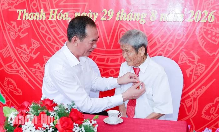 Phó Bí thư Tỉnh ủy Trịnh Tuấn Sinh gắn Huy hiệu 80 năm tuổi Đảng lên ngực áo đảng viên Trịnh Xuân Bảy.