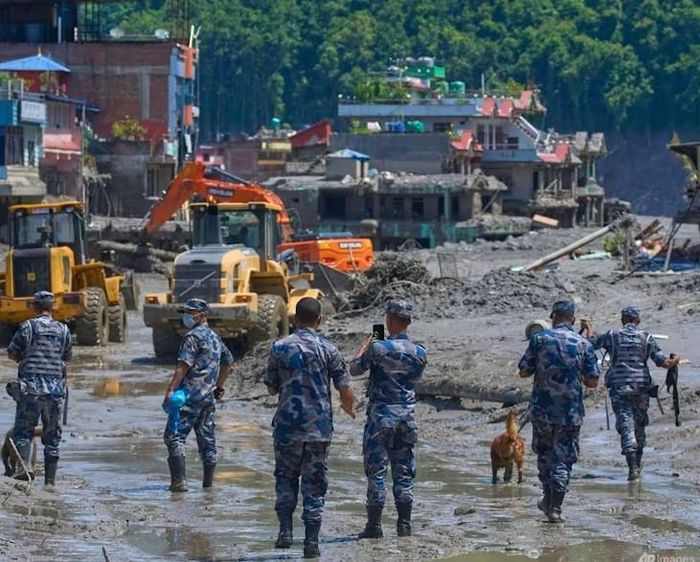 Cảnh sát Nepal theo dõi máy xúc dọn dẹp đất đá và bùn đất sau trận lũ quét tại huyện Nuwakot, Nepal. Ảnh: AP/Niranjan Shrestha