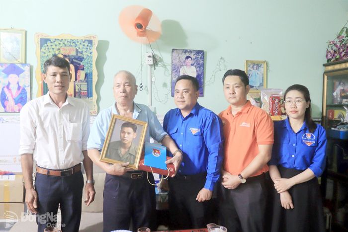 Đại diện Thành đoàn và Trường cao đẳng FPT Polytechnic tại Đồng Nai trao tặng ảnh phục dựng cho gia đình liệt sĩ Vũ Văn Vững. Ảnh: Nga Sơn