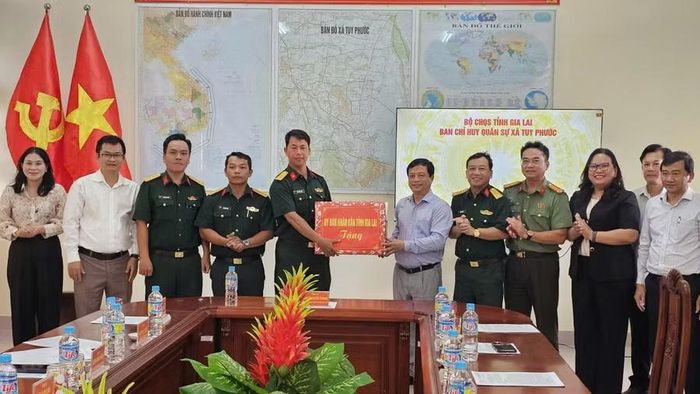 Phó Chủ tịch Thường trực UBND tỉnh Nguyễn Tuấn Thanh (thứ 6 từ phải sang) tặng quà cho Ban Chỉ huy Quân sự xã Tuy Phước. Ảnh: Đức Hải