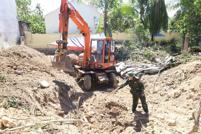 Trung tá Trần Quốc Thịnh xác định vị trí cần máy xúc hỗ trợ đào lớp đất phía trên.