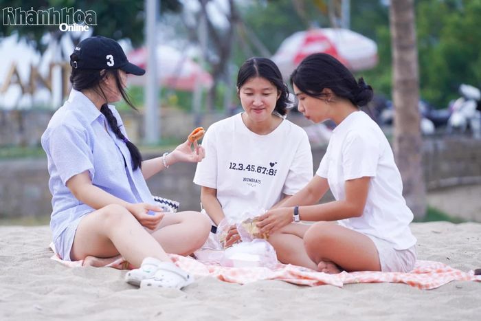 Nhóm bạn trẻ nghỉ ngơi, trò chuyện trên bãi cát.