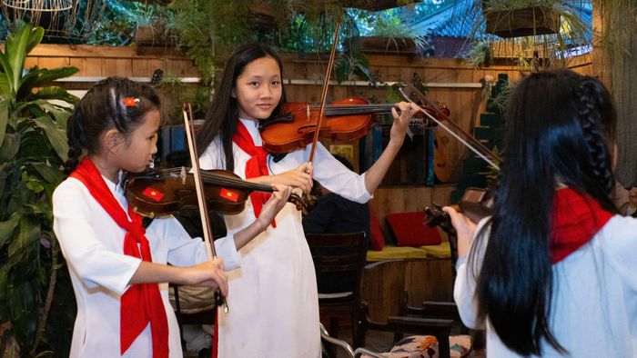 Các nghệ sĩ nhỏ tuổi biểu diễn violon trong không gian triển lãm