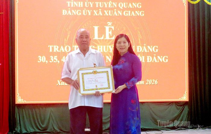 Đồng chí Lê Thị Thanh Trà trao Huy hiệu 65 tuổi Đảng cho đảng viên Hoàng Văn Thái, Chi bộ thôn Chang, Đảng bộ xã Xuân Giang.