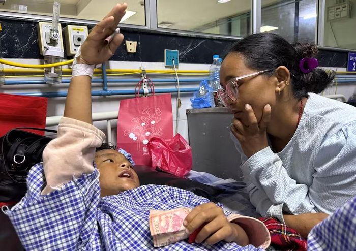 Hai mẹ con chị Tamang đoàn tụ tại bệnh viện. Trên tay cậu bé vẫn cầm 20 rupee. Ảnh Reuters.