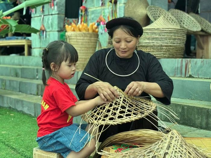 Các du khách nhí thích thú trải nghiệm thử làm sản phẩm thủ công cùng nghệ nhân.