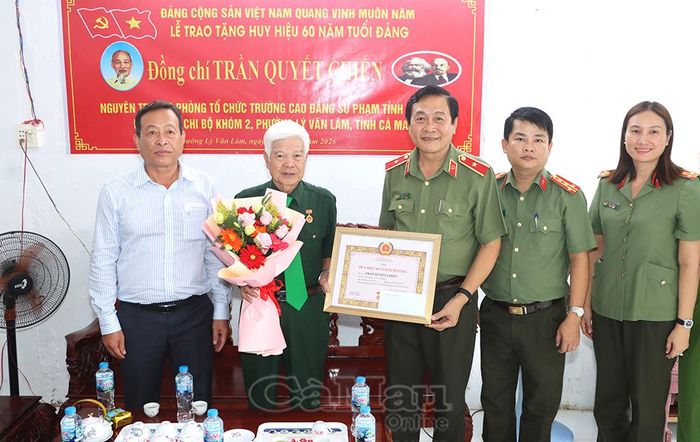 Thiếu tướng Hồ Việt Triều trao Huy hiệu 60 năm tuổi Đảng và tặng hoa chúc mừng đồng chí Trần Quyết Chiến.