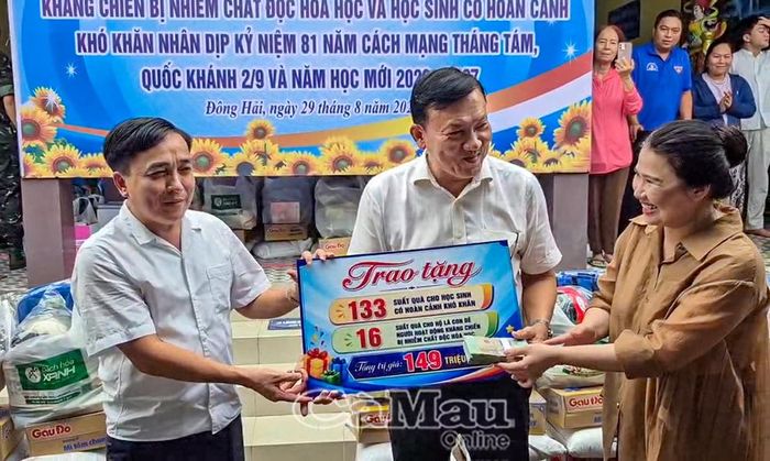 Gia đình ông Nguyễn Văn Sử, Chủ tịch UBND phường Bình Tân, TP Hồ Chí Minh (bìa trái), trao bảng tượng trưng quà tặng học sinh có hoàn cảnh khó khăn và con đẻ người hoạt động kháng chiến bị nhiễm chất độc hoá học cho đại diện lãnh đạo xã Đông Hải.
