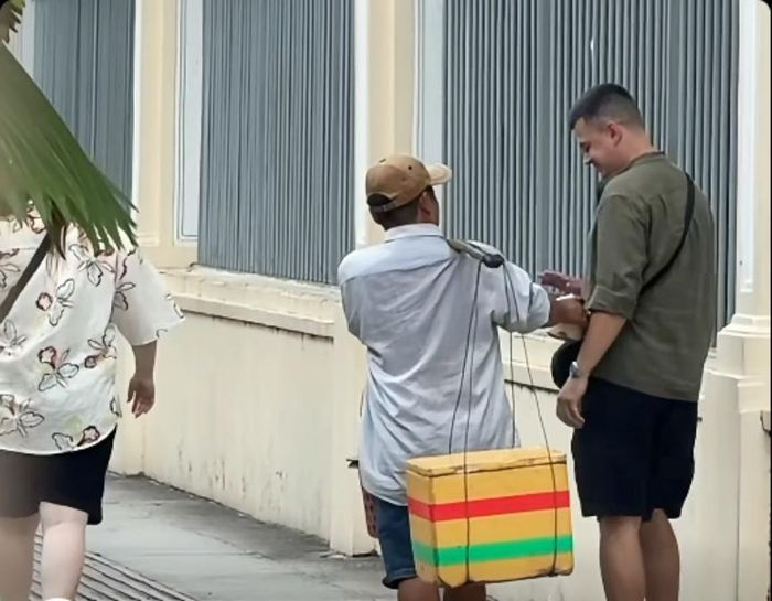 Người đàn ông liên tục chèo kéo, mời khách gánh dừa, mua dừa. (Ảnh cắt từ clip)