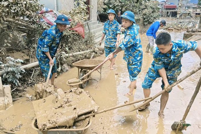 Cán bộ, chiến sĩ thu dọn vật liệu sau mưa lũ. Ảnh: Hoàng Thuần