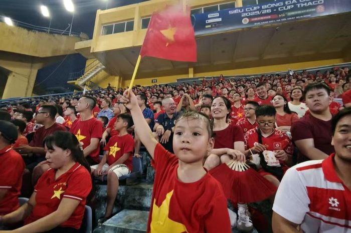 Một fan nhí của CLB Công an Hà Nội dơ cao cờ Tổ quốc cổ vũ đội nhà