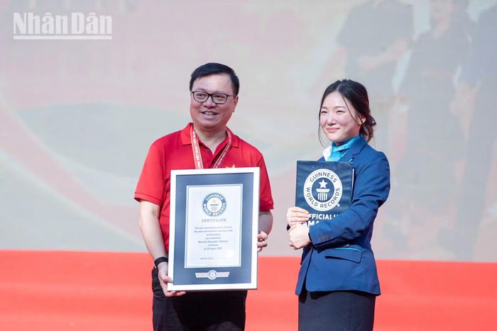 Đồng chí Lê Quốc Minh, Ủy viên Trung ương Đảng, Tổng Biên tập Báo Nhân Dân, Phó Trưởng ban Tuyên giáo Trung ương, Chủ tịch Hội Nhà báo Việt Nam thay mặt Ban tổ chức nhận chứng nhận Kỷ lục Guinness thế giới. (Ảnh: MINH DUY)