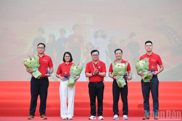 Tổng Biên tập Báo Nhân Dân Lê Quốc Minh tặng hoa và kỷ niệm chương cho các đơn vị đồng hành.