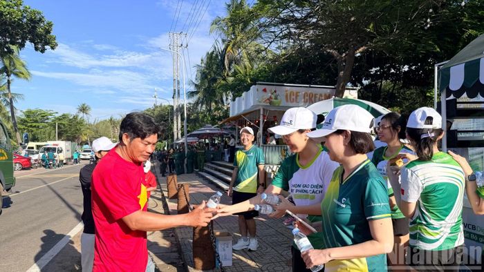 Nhân viên ngân hàng Vietcombank chi nhánh Bình Thuận tiếp nước cho các vận động viên. (Ảnh: Thanh Hải)