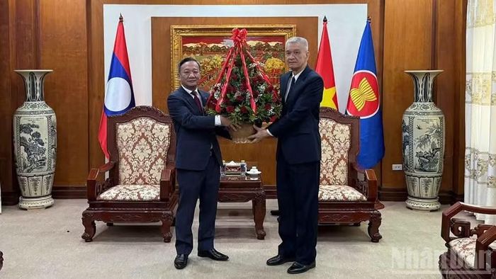 Đồng chí Anuphap Tunalom, Bí thư Trung ương Đảng Nhân dân Cách mạng Lào, Giám đốc Học viện Chính trị-Hành chính quốc gia Lào (bìa phải) tặng hoa chúc mừng Đại sứ quán Việt Nam tại Lào. (Ảnh: Cộng tác viên)