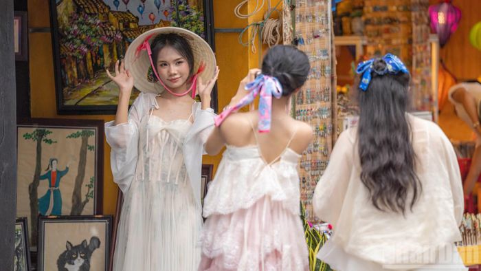 Thiếu nữ thướt tha trong tà váy bồng bềnh, e ấp tạo dáng cùng chiếc nón lá truyền thống trước một cửa hàng tranh nghệ thuật. Những góc nhỏ đậm chất thơ của Hội An luôn là phông nền hoàn hảo cho những bức ảnh thanh xuân.