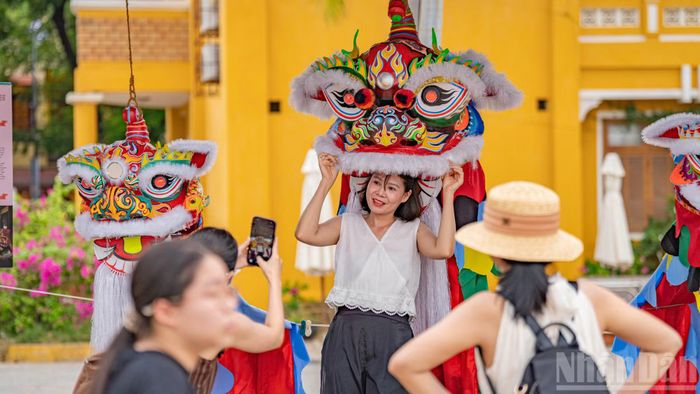 Sự tương tác trực tiếp biến di sản thành một trải nghiệm sống động. Một nữ du khách vô cùng thích thú khi được tự tay đội thử chiếc đầu múa lân sư rực rỡ sắc màu ngay tại không gian trưng bày nghệ thuật dân gian ngoài trời.