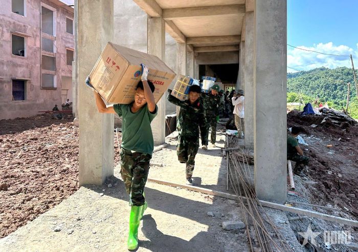 Chiến sĩ Trung đoàn 82, Sư đoàn 355, Quân khu 2 vận chuyển thiết bị phục vụ hoàn thiện Trường Phổ thông nội trú liên cấp Tiểu học và THCS xã Sín Thầu. Ảnh: QUANG THẮNG
