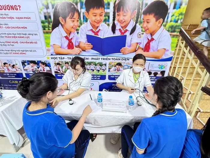 Tại các bàn đều có nhân viên y tế hướng dẫn các bước để học sinh khám sức khỏe.