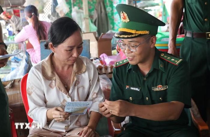 Giữa khu chợ biên giới, Đại úy Phạm Việt Tiến, Chính trị viên, phó Đồn Biên phòng Cửa khẩu Mỹ Quý Tây (tỉnh Tây Ninh), kiên nhẫn giải thích cho người dân những vấn đề liên quan đến an ninh, trật tự. (Ảnh: Bùi Giang/TTXVN)