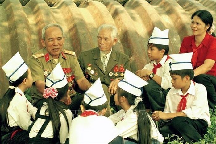 Đội viên trường THCS Mường Thanh (Điện Biên) nghe cựu đại tá Nông Văn Khâu, nguyên Phó Tư lệnh Quân khu II, Trưởng Ban Liên lạc chiến sĩ Điện Biên, Chủ tịch Hội Cựu chiến binh tỉnh Lai Châu kể chuyện về chiến dịch Điện Biên (2003). Ảnh: Thanh Hà/TTXVN