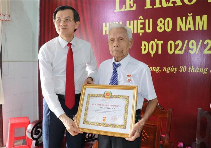 Đồng chí Đoàn Minh Huấn, Ủy viên Bộ Chính trị, Giám đốc Học viện Chính trị quốc gia Hồ Chí Minh trao Huy hiệu 80 năm tuổi Đảng cho đảng viên Phạm Thành Nối, phường Hòa Thuận.