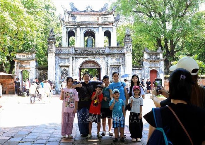 Một gia đình chụp ảnh lưu niệm trước cổng Văn Miếu - Quốc Tử Giám. Ảnh: Tuấn Anh/TTXVN
