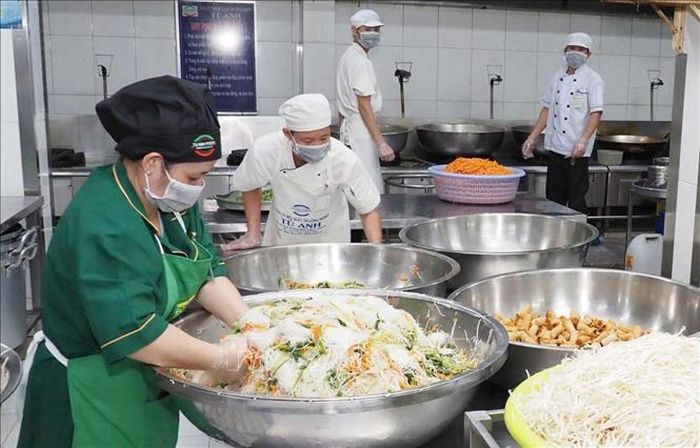 Nhân viên Công ty TNHH MTV Suất ăn công nghiệp Tú Anh, đơn vị cung cấp suất ăn cho nhiều trường học tại TP Hồ Chí Minh đang chế biến thức ăn trước khi giao cho trường học. Ảnh: Đinh Hằng/TTXVN