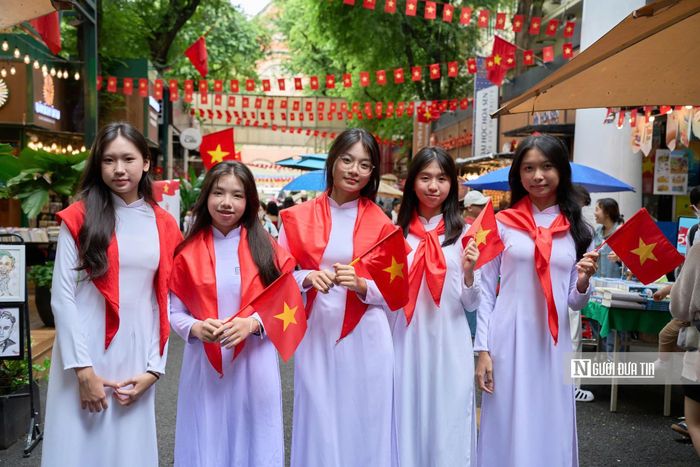 Nhóm bạn trẻ diện áo dài, cầm quốc kỳ check-in trong không gian đường sách Tp.HCM.
