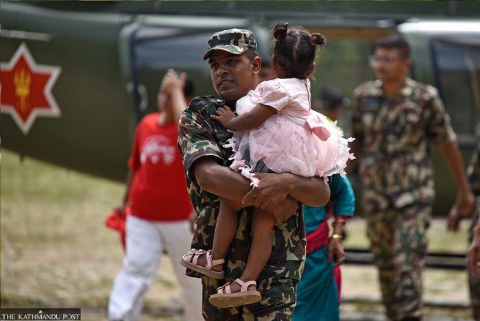 Một binh sĩ thuộc quân đội Nepal cõng một đứa trẻ khác bị mắc kẹt đến nơi an toàn. Ảnh: Angad Dhakal/TKP