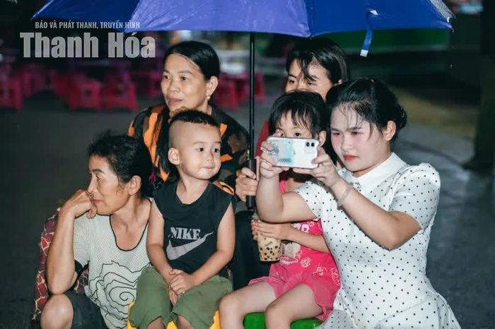 Dù mưa, nhưng không ngăn được người xem che ô, mặc áo mưa ngồi lại.