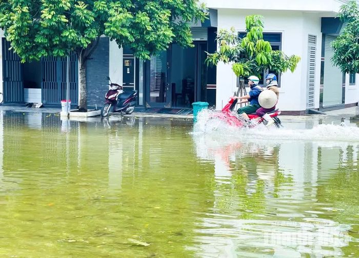 Mỗi khi có xe máy chạy qua, nước dạt sang hai bên tạo thành những đợt sóng tạt vào vỉa hè và nhà dân.