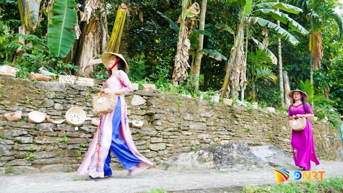 Chị em phụ nữ tự tin trình diễn trang phục áo dài kết hợp phụ kiện làm từ mo cau bên bờ đá rêu phong làng cổ. Ảnh: DIỄM LỆ