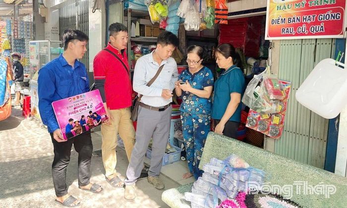 Đoàn viên, thanh niên hướng dẫn tiểu thương chợ Hậu Mỹ Trinh tạo và sử dụng mã QR thanh toán không dùng tiền mặt.