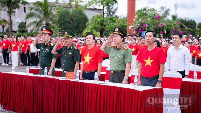 Đại biểu, các lực lượng và người dân thực hiện lễ chào cờ - Ảnh: H.L