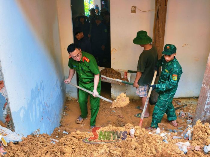 Cán bộ Đồn Biên phòng Mường Lạn và Công an xã Mường Lạn hỗ trợ gia đình ông Hà Văn May dọn dẹp bùn đất. (Ảnh Mạnh Phương)