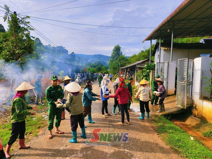 Cán bộ, chiến sĩ Đồn Biên phòng Mường Lạn cùng người dân di chuyển tài sản của gia đình ông May đến nơi an toàn. (Ảnh Mạnh Phương)