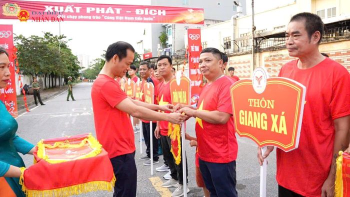 Đại diện Ban tổ chức trân trọng trao cờ tham gia hoạt động cho các khối, đơn vị xuất phát. Khoảnh khắc những lá cờ đỏ thắm tung bay trong gió mùa thu cũng là lúc hiệu lệnh bắt đầu vang lên.