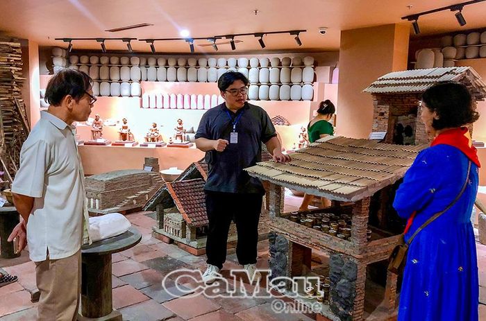 Thuyết minh viên giới thiệu đến du khách các mô hình lò nung gốm qua từng thời kỳ phát triển của làng gốm Bát Tràng.