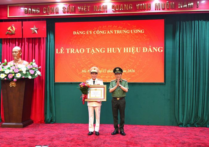 Bộ trưởng Bộ Công an Lương Tam Quang trao Giấy chứng nhận, gắn Huy hiệu Đảng và tặng hoa chúc mừng Thứ trưởng Lê Quốc Hùng.