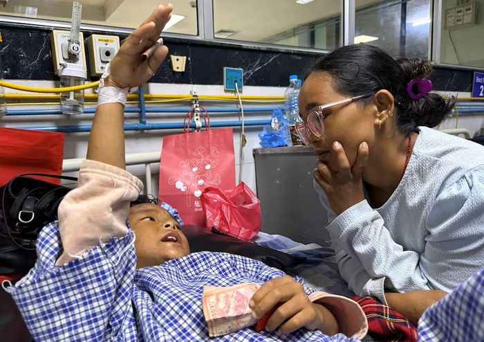 Zoyal Ghale đoàn tụ với mẹ tại bệnh viện, trong tay vẫn cầm chắc hai tờ tiền được cánh sát tặng khi tìm thấy ở trên cây. Ảnh: Reuters