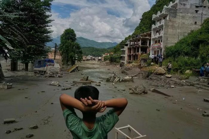 Một đứa trẻ đứng nhìn những thiệt hại do lũ lụt gây ra dọc sông Trishuli, Nepal - Ảnh: AP