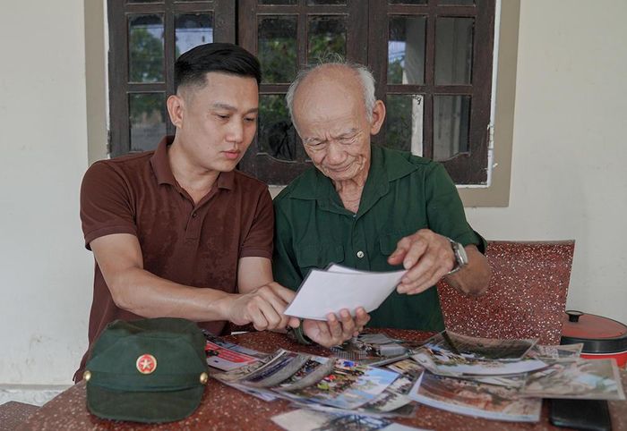 Ông Lê Văn Phước xem lại những hình ảnh và tư liệu trong quá trình trò chuyện về những năm tháng quân ngũ.