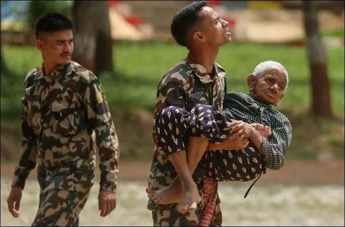 Một binh sĩ bế cụ già được sơ tán khỏi khu vực bị ảnh hưởng bởi lũ quét và sạt lở đất tại doanh trại Maithili, một trung tâm huấn luyện quân đội ở Trishuli, huyện Nuwakot, Nepal, ngày 30-8. Ảnh: Reuters
