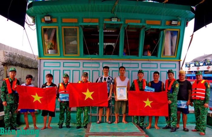 Cán bộ Hải đoàn Biên phòng 38 tuyên truyền pháp luật, tặng cờ Tổ quốc và ảnh Bác Hồ cho ngư dân. Ảnh: Văn Vinh