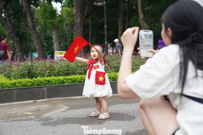 Một em nhỏ trong bộ váy trắng cầm cờ đỏ sao vàng được mẹ ghi lại khoảnh khắc kỷ niệm dịp Quốc khánh 2/9.