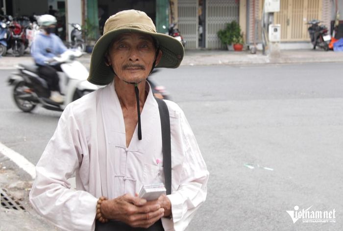Sau khi nhận cơm từ quán, ông Hậu lại tranh thủ đi bán vé số. Ảnh: Hà Nguyễn